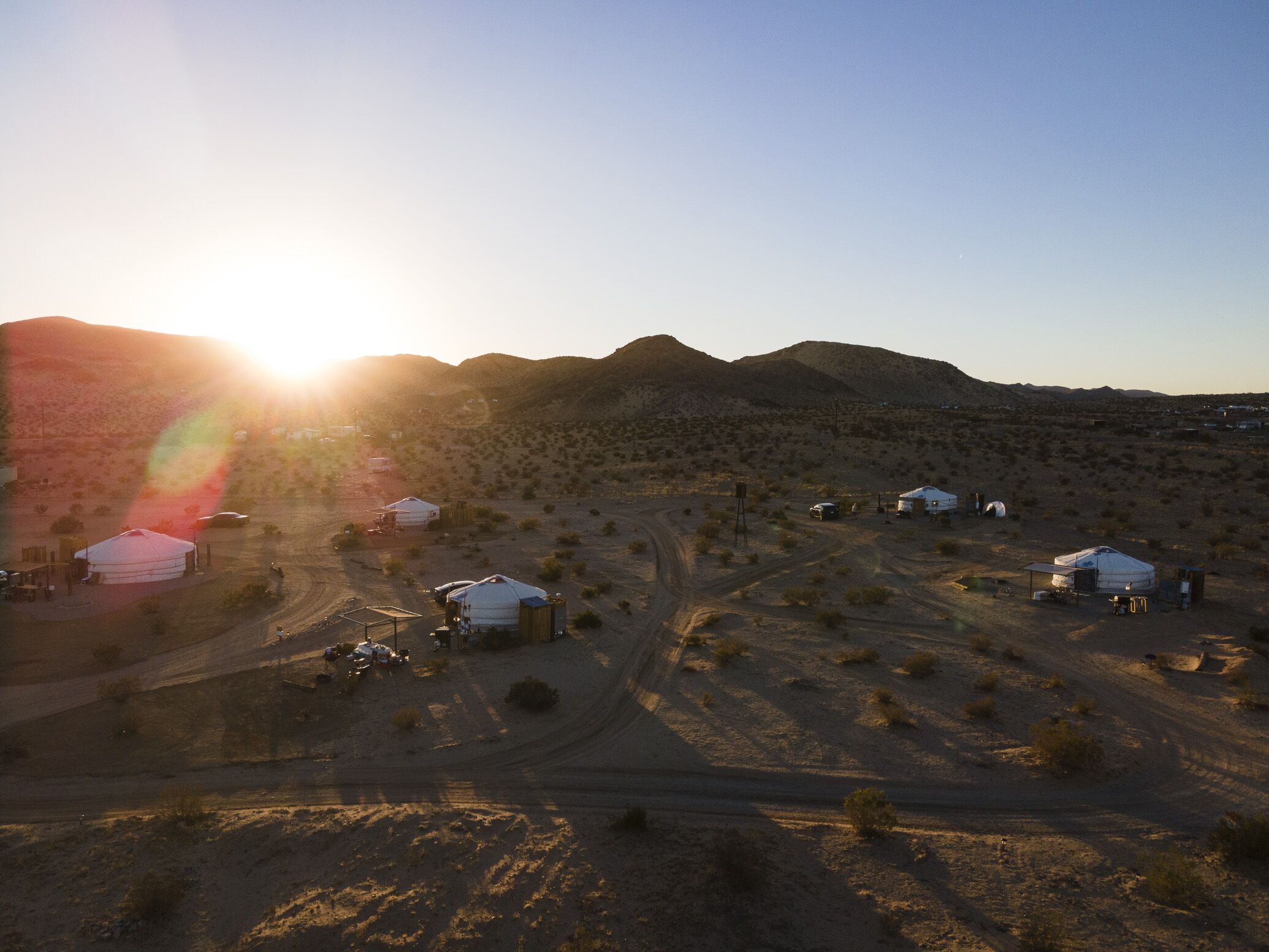 A desert landscape with yurts and a dirt road.