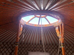 A yurt with a circular wooden frame, a central opening, and a lattice wall.