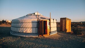 A traditional yurt with a wooden door and a small wooden structure beside it. - 28 Palms Ranch (Twentynine Palms)