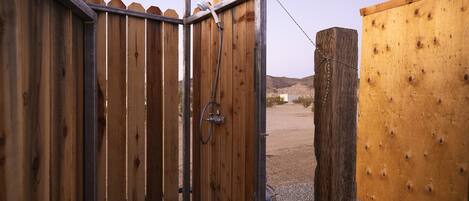 Una valla de madera con un portón de metal, un poste de madera y un área de grava.