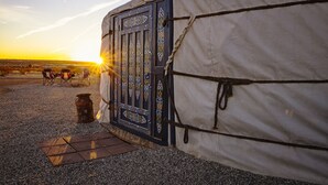 A traditional yurt with a decorative door, a small fire pit, and two chairs outside. - 28 Palms Ranch (Twentynine Palms)