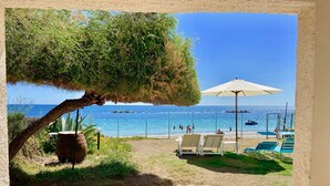 A stone pathway leading to beach chairs and an umbrella, overlooking a clear blue sea with people in the water. - Spacious Beachfront Villa (Porto Columbu-Perd'È Sali)