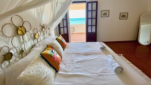 A bedroom with a bed, a canopy, a large mirror, and a view of the beach. - Spacious Beachfront Villa (Porto Columbu-Perd'È Sali)