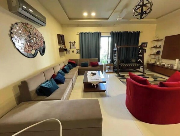 A living room with a sofa, a red chair, a coffee table, and a decorative wall piece.