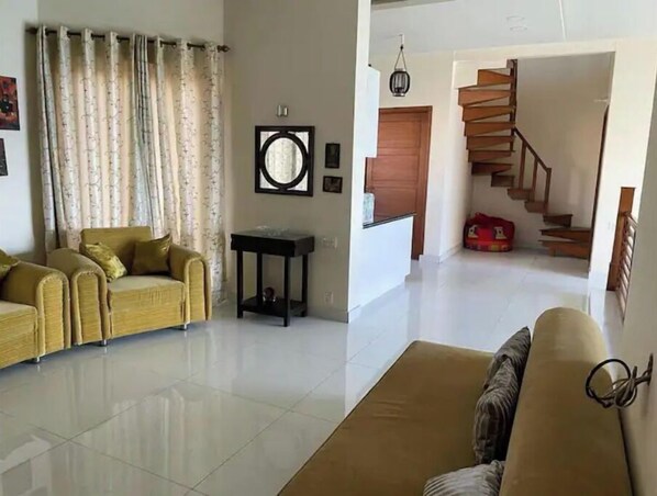 A living room with a sofa, a coffee table, and a staircase leading to an upper floor.