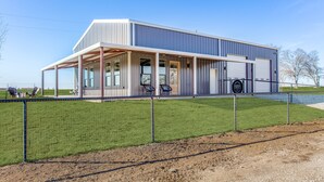 A modern building with a covered patio area, large windows, and a fenced outdoor space.