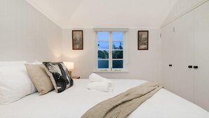 A bedroom with a large bed, a window, and a wardrobe. - The Indooroopilly Queenslander 4BDR Home (Indooroopilly)