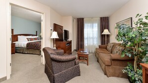 A hotel room with a bed, a sofa, a chair, a small table, a TV, and a plant. - 1 Bedroom | Indoor Pool + Hot Tub Access (Albuquerque)