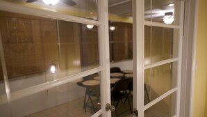 Huone, jossa on lasiovi, joka johtaa ruokailutilaan, jossa on pöytiä ja tuoleja.
