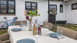 An outdoor dining area with a table set for two, surrounded by wicker chairs. - Awesome apartment in Allinge with WiFi (Allinge)
