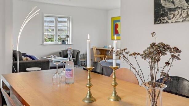 A dining area with a wooden table, two brass candle holders, a bottle of LORINA, and a vase with dried flowers. - Awesome apartment in Allinge with WiFi (Allinge)