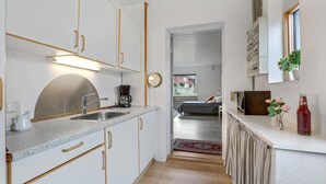 A modern kitchen with white cabinets, a stainless steel sink, and a coffee maker. There is a small window with a view of the outside. - Awesome apartment in Allinge with WiFi (Allinge)