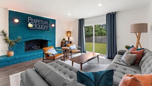 En moderne stue med en teal murstenspejs, sofasæt, sofabord og spiseplads.