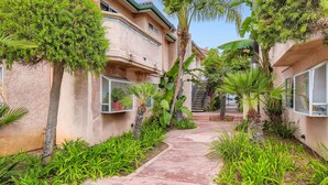 A residential building with a narrow pathway surrounded by lush greenery and palm trees. - 1 Block to Beach/Restaurants/Bars, Remodeled, 2-Car Garage w/fee, Yard, Sleep 10 (San Diego)