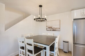 A modern kitchen with a dark wooden table, white chairs, a stainless steel refrigerator, and a chandelier. - 1 Block to Beach/Restaurants/Bars, Remodeled, 2-Car Garage w/fee, Yard, Sleep 10 (San Diego)
