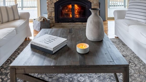 Una sala de estar con chimenea de piedra, un televisor de pantalla plana montado arriba y dos sofás.