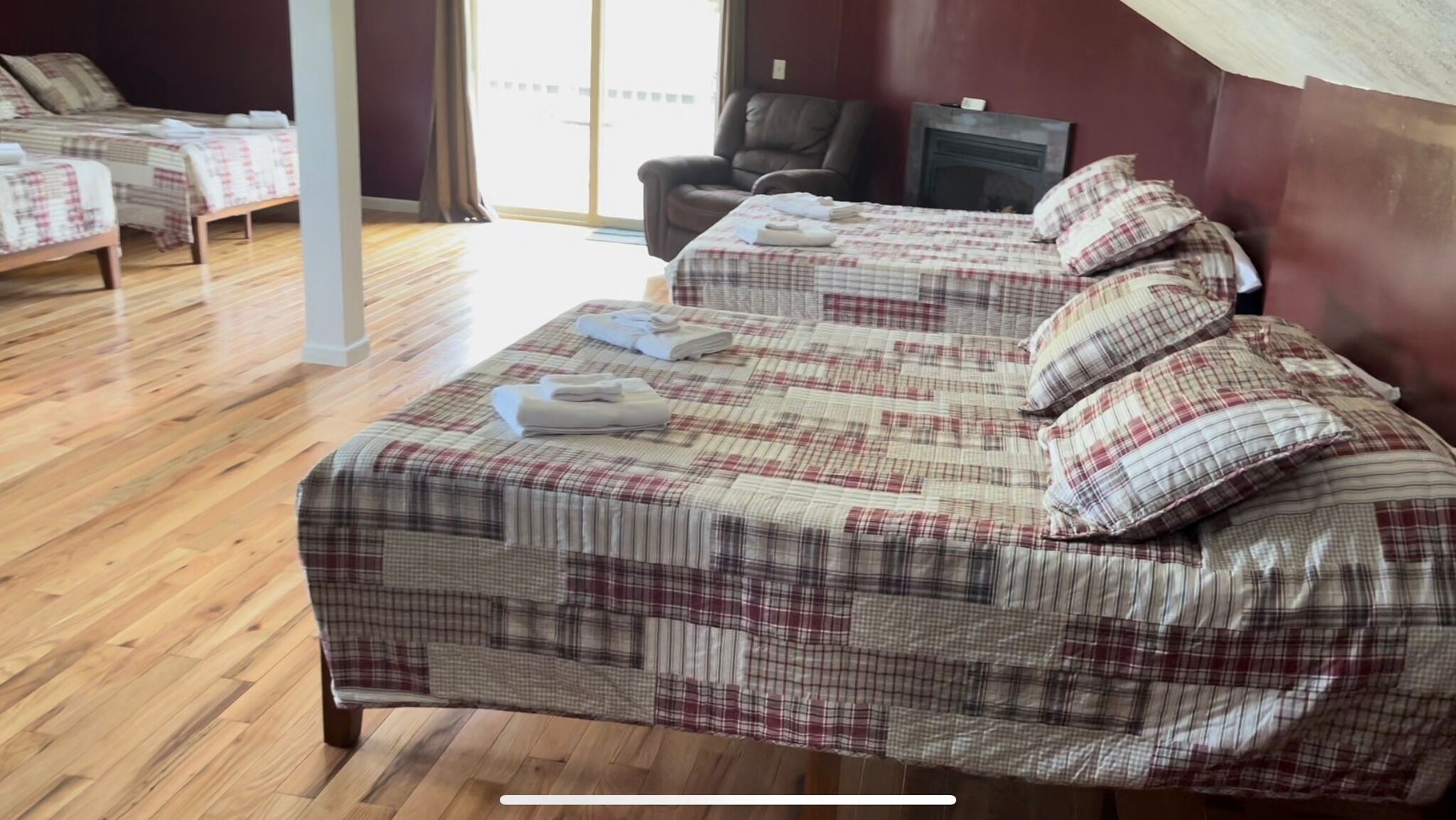 A hotel room with two beds, a massage chair, and a view of the outdoors.
