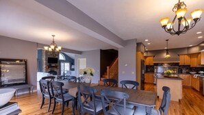 Una cocina moderna con armarios de madera, una isla central y una zona de comedor con mesa y sillas de madera.