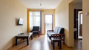 Un salon comprenant un canapé, un fauteuil, une table et un téléviseur fixé au mur.