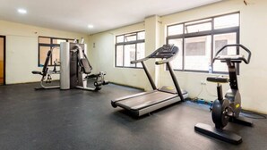 Une salle de sport équipée de tapis de course, d’un appareil elliptique et de machines de musculation.