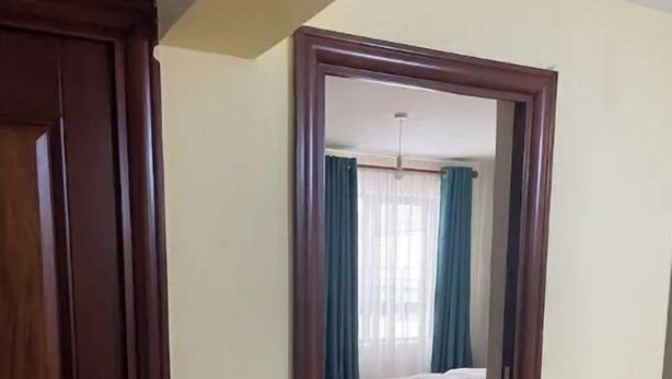 Ein Zimmer mit einem Bett, einer Tür und Blick durch einen Durchgang.