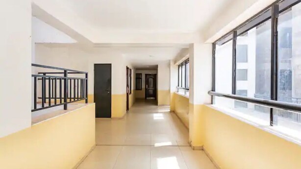 A corridor with yellow walls, black railings, and large windows. - Lovely private room with free parking on premises (Nairobi)