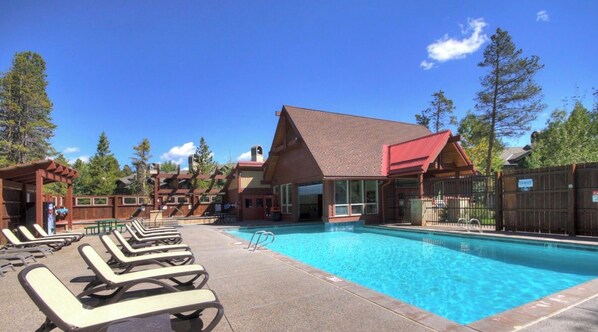 A pool area with lounge chairs and a building with a red roof.