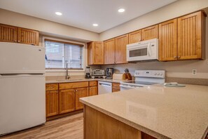 A kitchen with wooden cabinets, a microwave, a refrigerator, a toaster, and a dishwasher. - Townhome Four O'Clock  (Breckenridge)