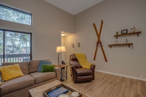 A living room with a brown leather sofa, a brown leather armchair, a small table with a lamp, and a large window. - Townhome Four O'Clock  (Breckenridge)