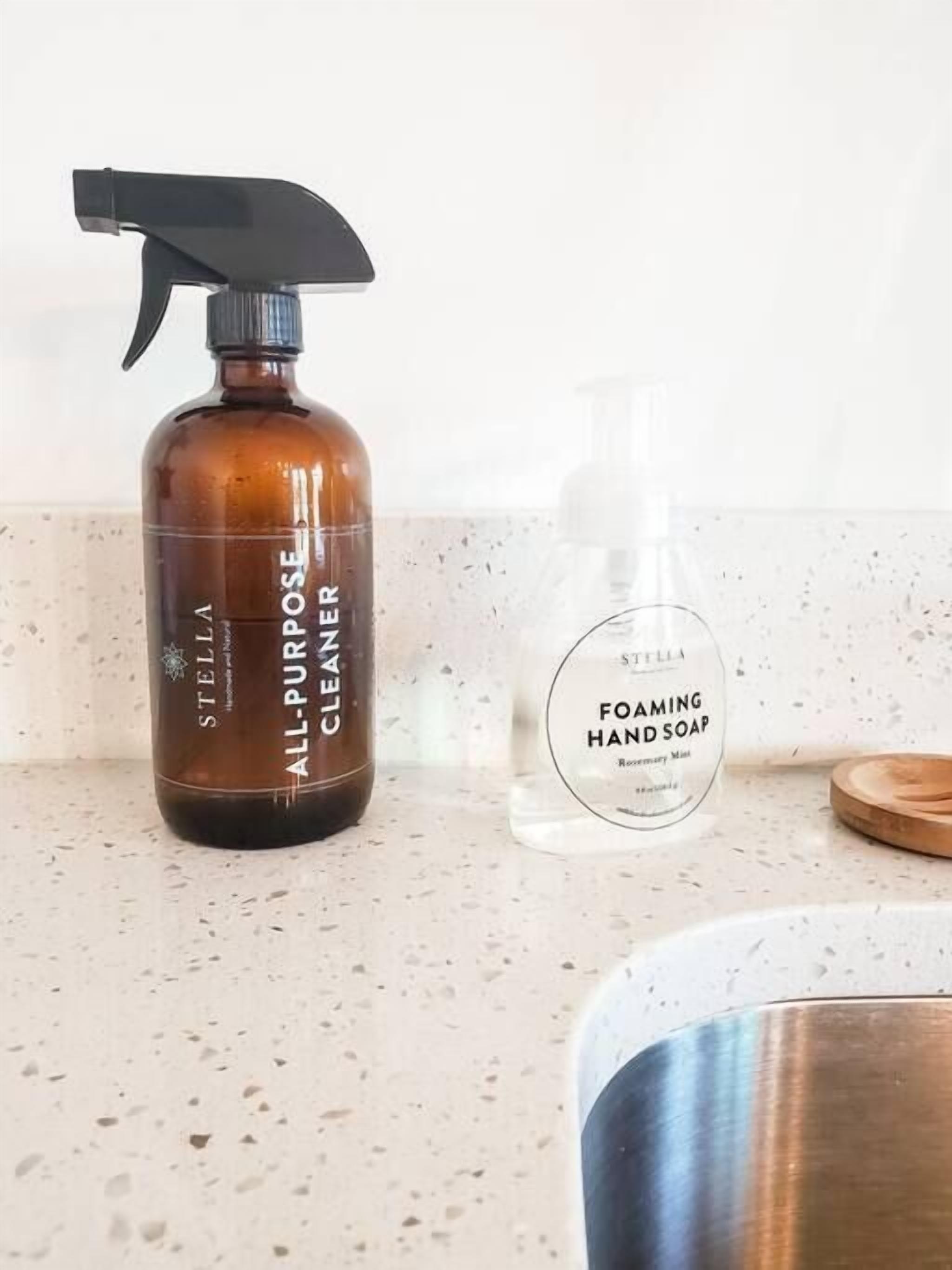 Una encimera con una botella marrón etiquetada 'Stella All-Purpose Cleaner' y una botella transparente etiquetada 'Stella Foaming Hand Soap'.