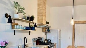 Une cuisine moderne avec des meubles en bois, une cuisinière encastrée et un petit coin repas comprenant une table et des tabourets de bar.