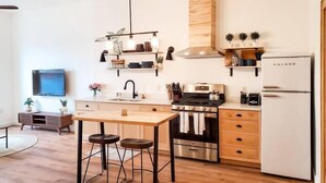 Une cuisine moderne dotée d’un îlot central, d’appareils électroménagers en acier inoxydable, de meubles de rangement en bois et d’un four encastré.