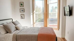 Une chambre à coucher avec un lit, une fenêtre et un téléviseur à écran plat.
