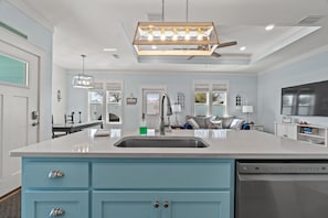 Una cocina moderna con una isla central, electrodomésticos de acero inoxidable y un ventilador de techo.
