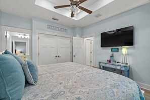 A bedroom with a bed, a ceiling fan, a TV, and a dresser. - Golf Cart Included, West Side PCB (Panama City Beach)