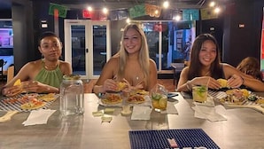 A restaurant interior with tables, chairs, and hanging decorations. - Beach Dorms San Juan (San Juan)