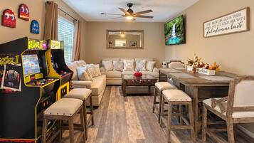 A living room with a sofa, coffee table, and arcade games.