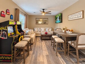 A living room with a sofa, coffee table, and arcade games. - Elegant Vacation- 2 miles to Dollywood- Arcades & More (Sevierville)