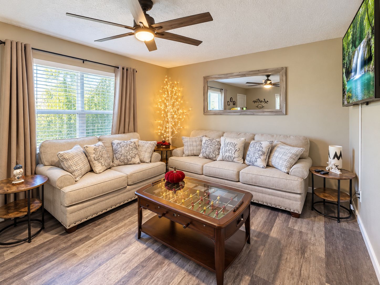 A living room with two sofas, a coffee table, a fireplace, and a ceiling fan.