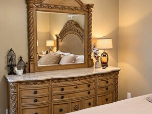 A bedroom with a large ornate mirror, a bed with multiple pillows, a nightstand with a lamp, and a dresser with drawers. - Elegant Vacation- 2 miles to Dollywood- Arcades & More (Sevierville)