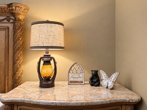 A marble countertop with a table lamp, a decorative bear figurine, a sign, and a butterfly ornament.