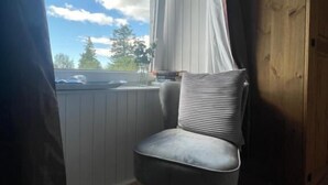 A corner room with a window, a chair, and a wooden door. - Taynuilt Guest House (Taynuilt)
