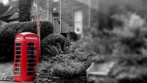 A red telephone booth in a residential area with houses in the background. - Taynuilt Guest House (Taynuilt)