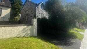 A stone house with a sloped roof, a paved driveway, and a grassy area. - Taynuilt Guest House (Taynuilt)