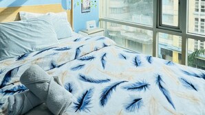 A bedroom with a bed, a window, and a wall with artwork.