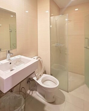 A modern bathroom with a sink, toilet, and glass shower enclosure. - HENRY & ADICHE  EMPERADOR BUILDING (Pasay)