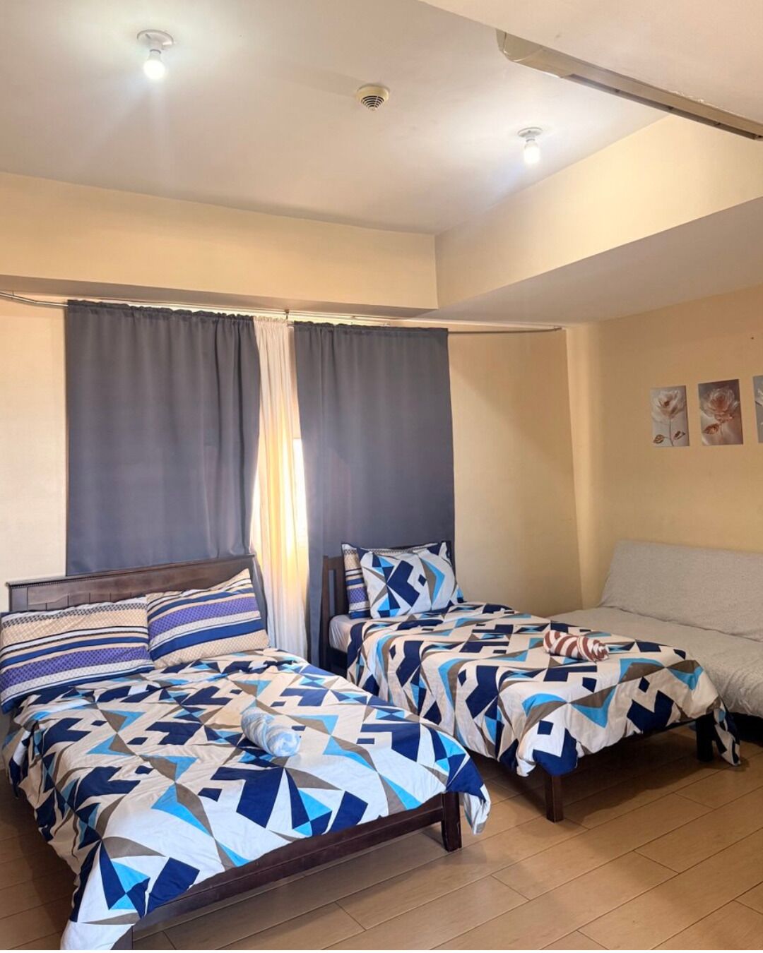 Ein Hotelzimmer mit zwei Betten, einer Schlafcouch und einer Deckenleuchte.