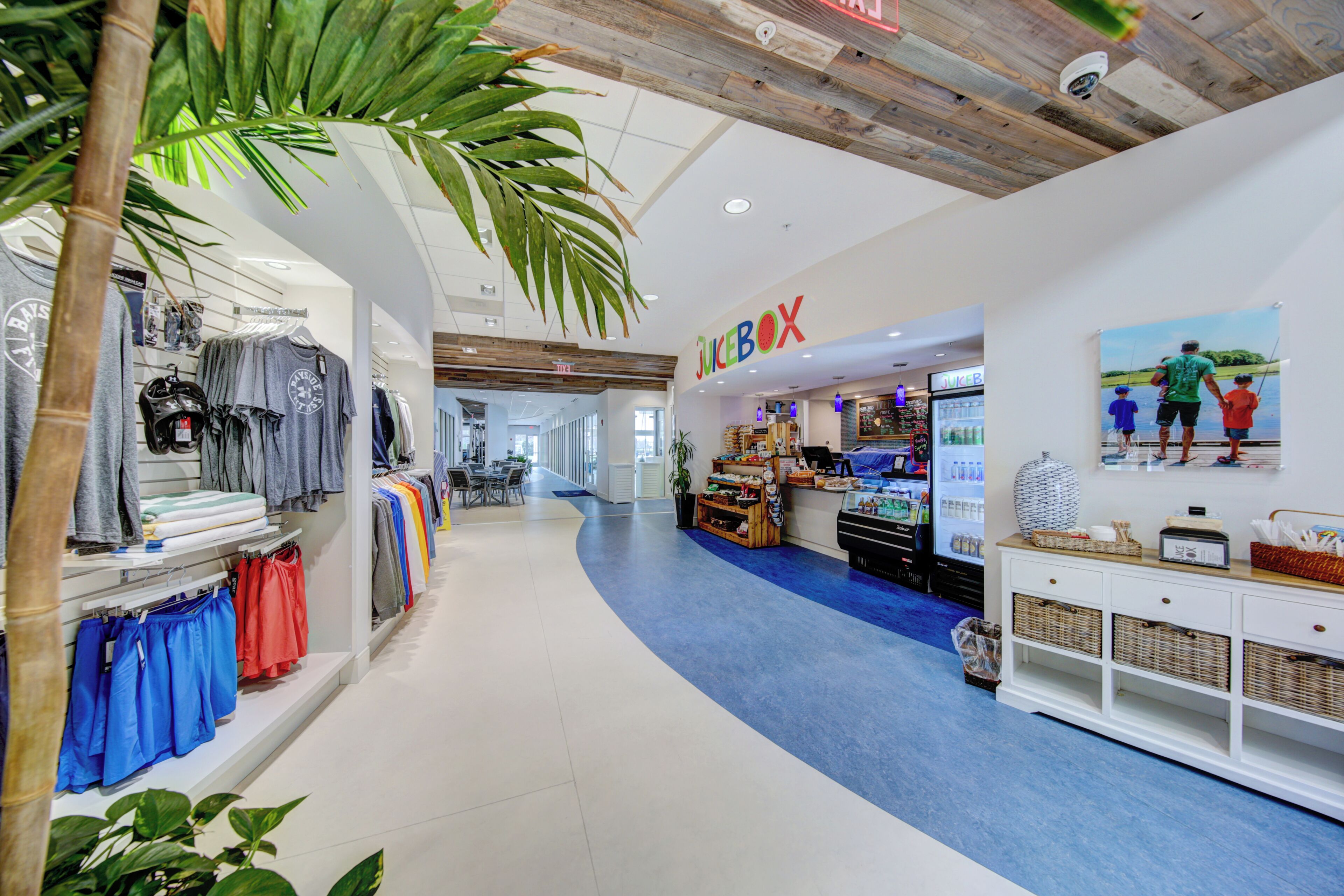 A clothing store with a blue carpet, wooden ceiling, and a juice bar.