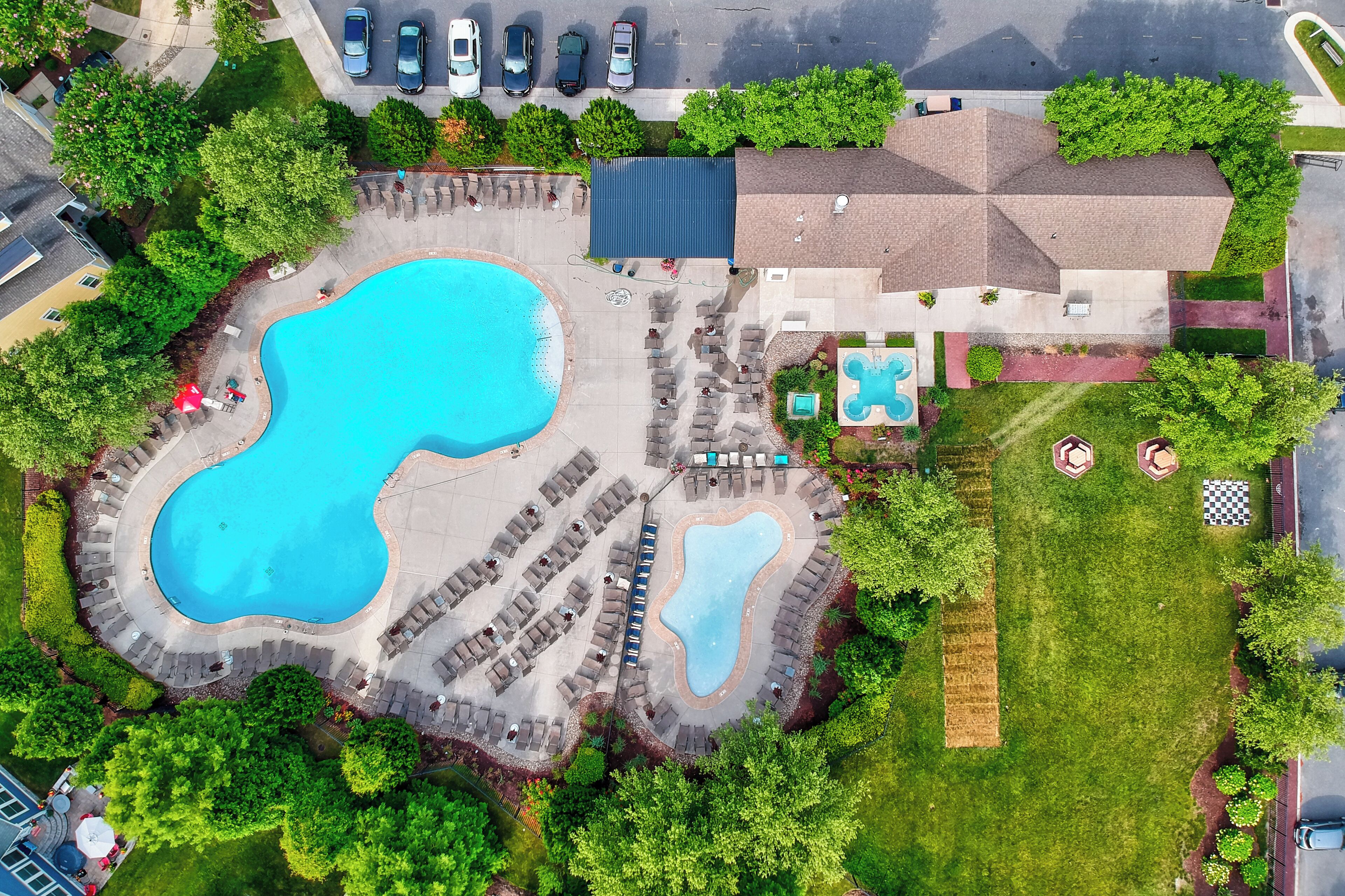 Vue aérienne d’une propriété dotée d’une grande piscine, de plusieurs espaces de détente et d’un parking.