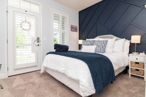 A bedroom with a bed, bedside tables, a door with a window, and a wall with a geometric pattern. - Beds Made, 2 King Suites, 2 Living Rooms, Bikes & Bayside Resort Pools, Courts (Selbyville)